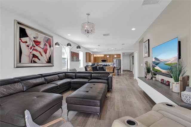 living room with a notable chandelier and light hardwood / wood-style floors