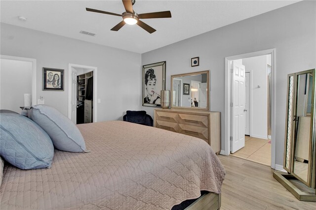 bedroom featuring ensuite bathroom, ceiling fan, a spacious closet, light hardwood / wood-style flooring, and a closet