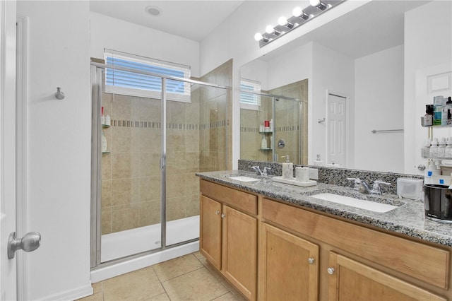 bathroom with a shower with door, vanity, and tile patterned flooring