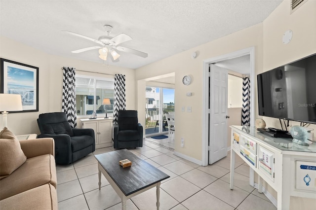 living room with ceiling fan, light tile patterned floors, and a textured ceiling