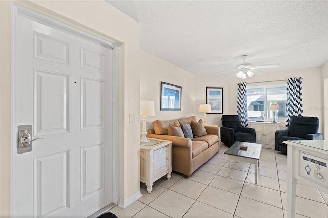 living room featuring ceiling fan, light tile patterned floors, and a textured ceiling