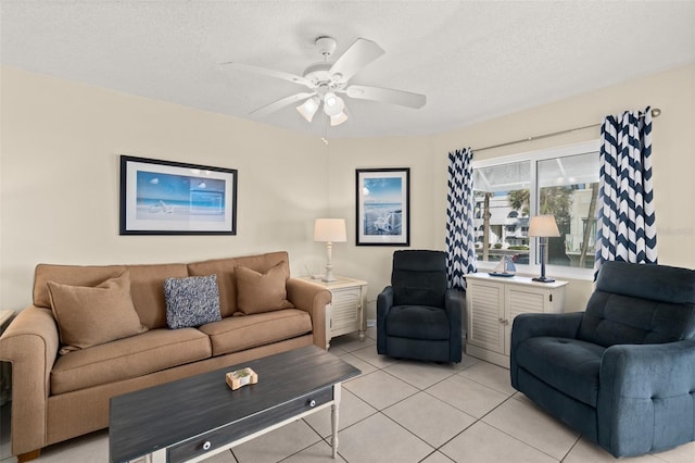 living room featuring ceiling fan, light tile patterned flooring, and a textured ceiling