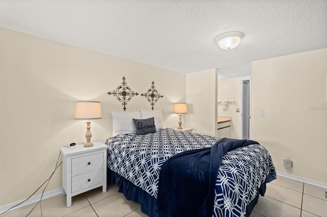 bedroom with light tile patterned flooring, a textured ceiling, and ensuite bath