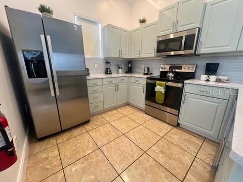 kitchen featuring stainless steel appliances, gray cabinets, and tasteful backsplash