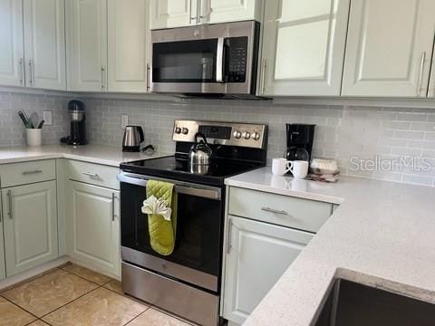 kitchen with backsplash, light tile patterned floors, and stainless steel appliances