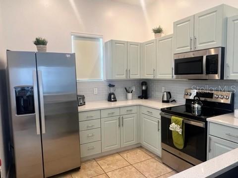 kitchen with appliances with stainless steel finishes, tasteful backsplash, gray cabinetry, and light tile patterned flooring