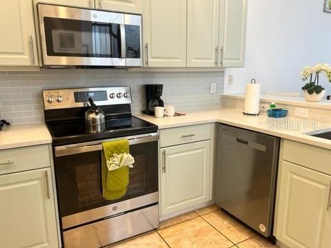 kitchen featuring light tile patterned floors, stainless steel appliances, and tasteful backsplash