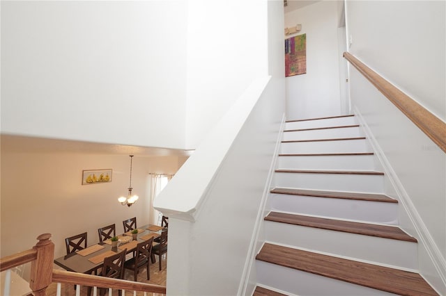 staircase featuring hardwood / wood-style floors and an inviting chandelier