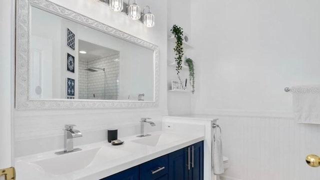 bathroom with toilet, vanity, and tiled shower