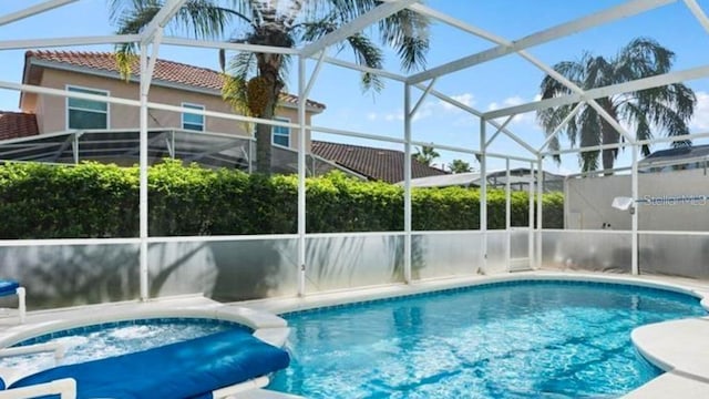 view of pool featuring glass enclosure and an in ground hot tub