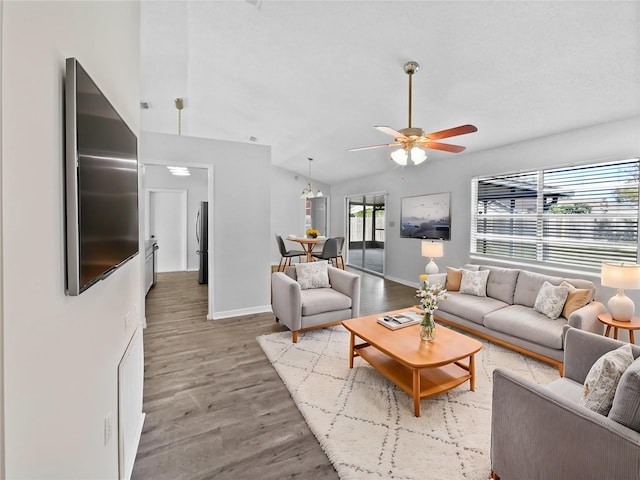 living room with ceiling fan, a healthy amount of sunlight, wood-type flooring, and lofted ceiling