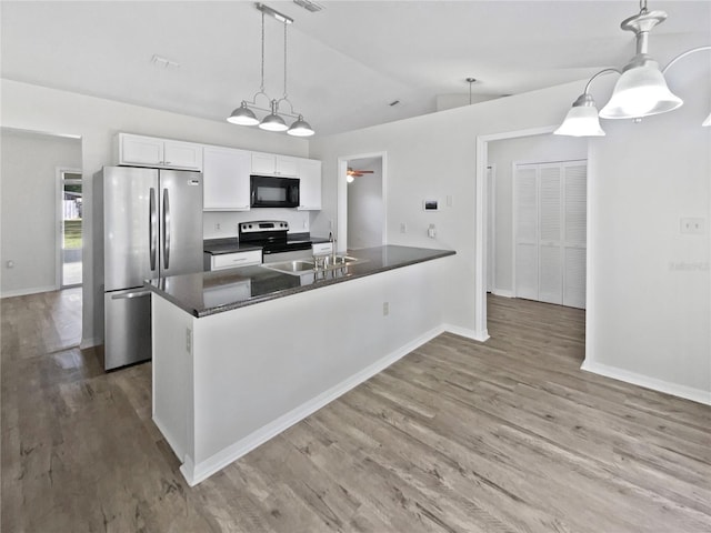 kitchen featuring hardwood / wood-style floors, lofted ceiling, hanging light fixtures, appliances with stainless steel finishes, and white cabinetry