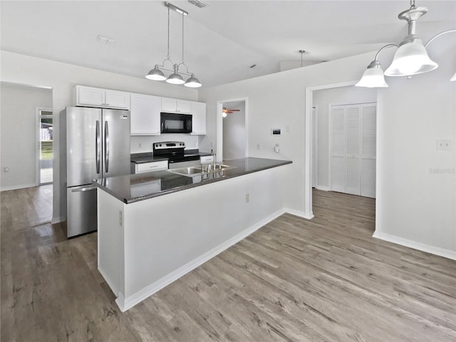 5119 Timber Ridge Trl, Ocoee, FL 34761 - kitchen featuring appliances with stainless steel finishes, lofted ceiling, dark countertops, white cabinetry, and wood finished floors