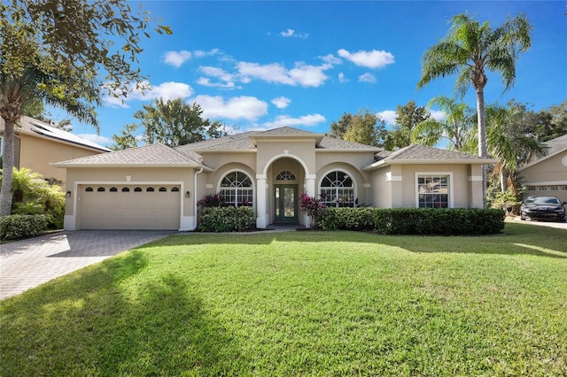 mediterranean / spanish-style home featuring a front lawn and a garage