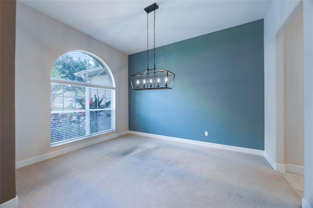 unfurnished room with carpet flooring and a notable chandelier