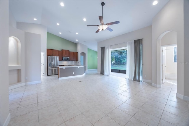 unfurnished living room with ceiling fan, light tile patterned floors, and high vaulted ceiling