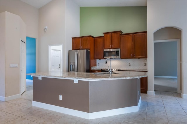 kitchen with a center island with sink, high vaulted ceiling, light tile patterned floors, and appliances with stainless steel finishes