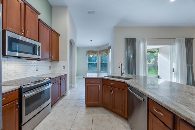 kitchen with sink, appliances with stainless steel finishes, decorative light fixtures, light tile patterned flooring, and light stone counters