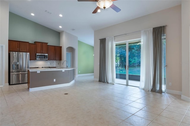 kitchen with ceiling fan, stainless steel appliances, high vaulted ceiling, a kitchen bar, and light tile patterned floors