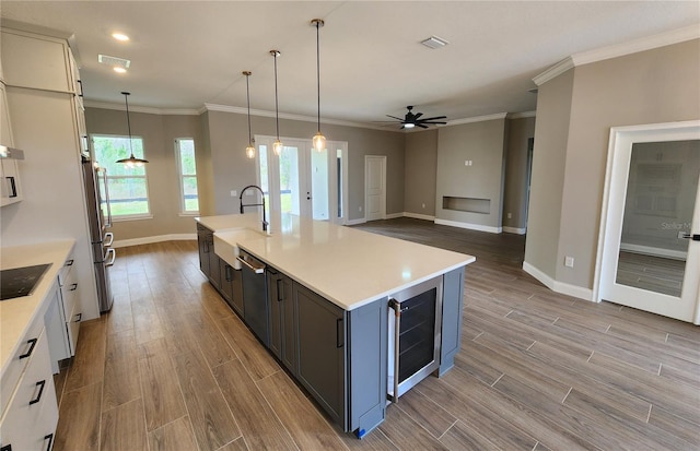 kitchen with beverage cooler, visible vents, white cabinets, appliances with stainless steel finishes, and light countertops