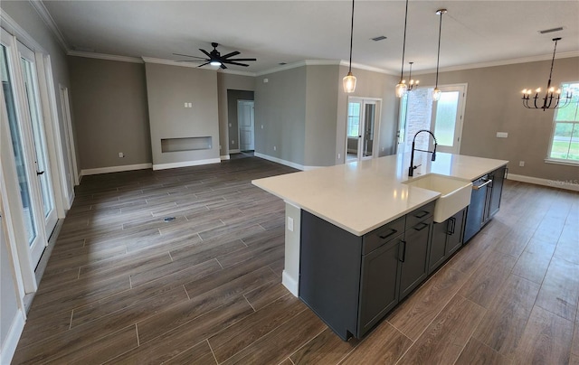 kitchen featuring light countertops, hanging light fixtures, a sink, and a center island with sink