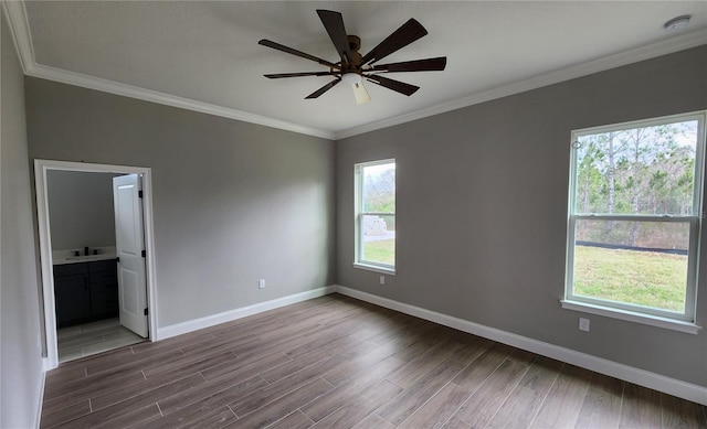 unfurnished bedroom featuring ornamental molding, ensuite bathroom, baseboards, and wood finished floors