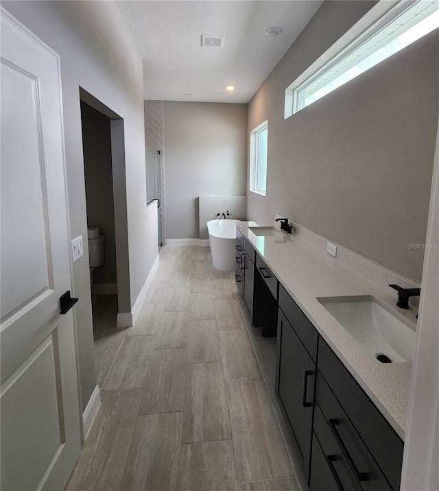 full bathroom featuring a freestanding tub, visible vents, a sink, and a stall shower