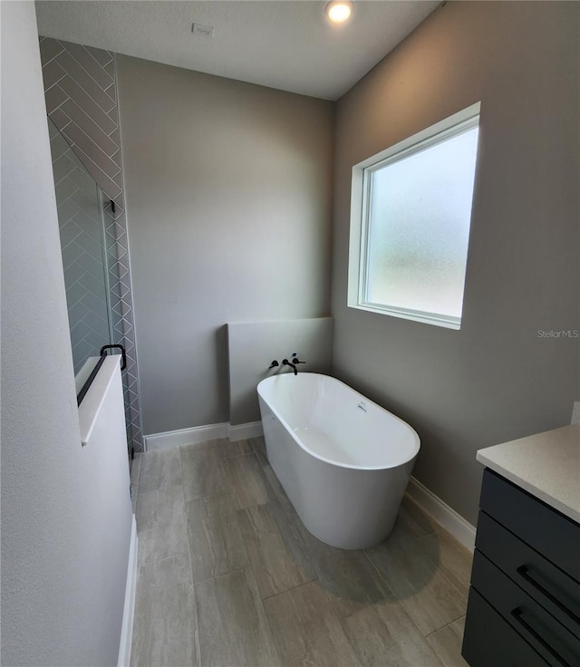 bathroom with a soaking tub, vanity, and baseboards