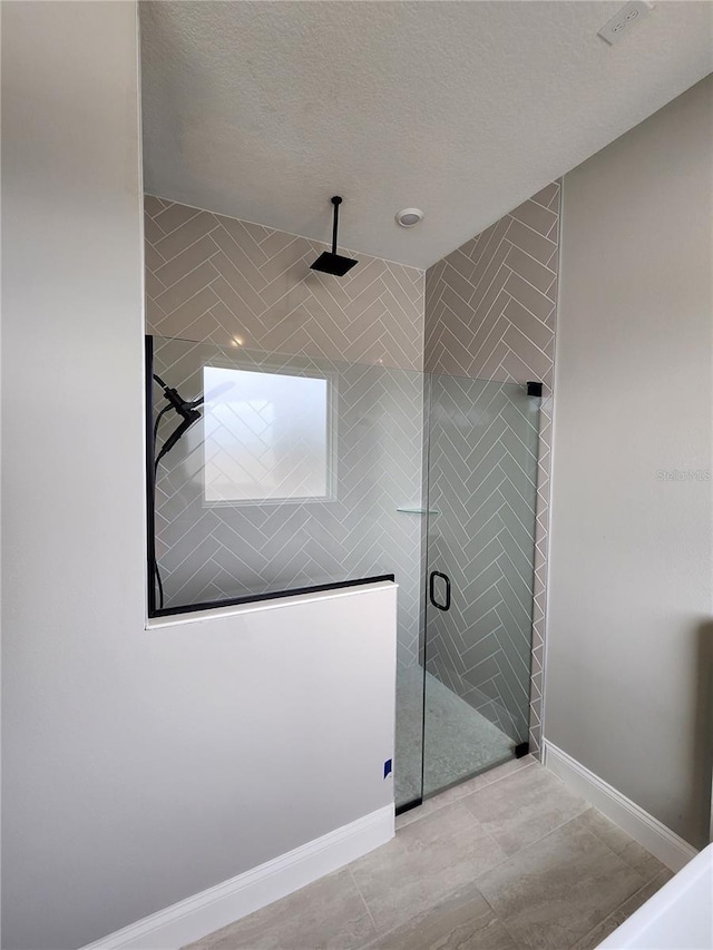 bathroom featuring baseboards, a shower stall, and a textured ceiling