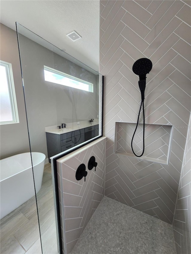 full bathroom featuring visible vents, a freestanding bath, and tiled shower