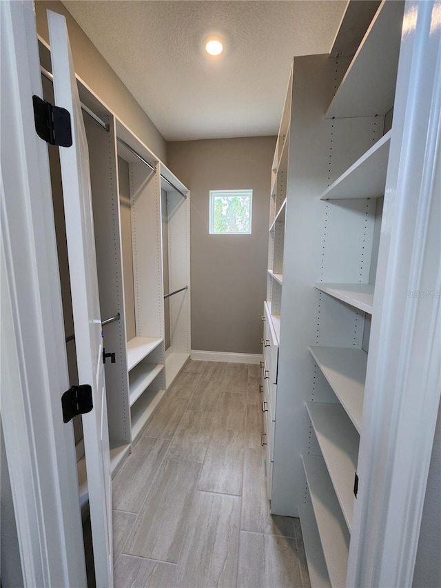 walk in closet with light wood-style flooring