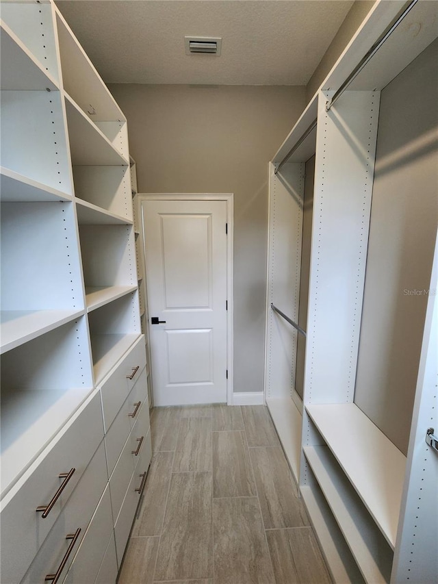 spacious closet with wood tiled floor and visible vents