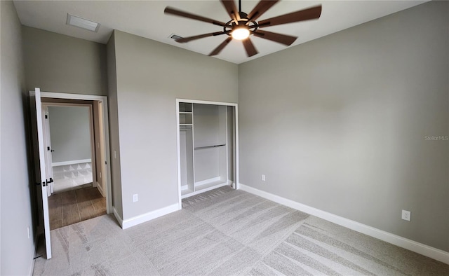 unfurnished bedroom featuring light carpet, ceiling fan, a closet, and baseboards