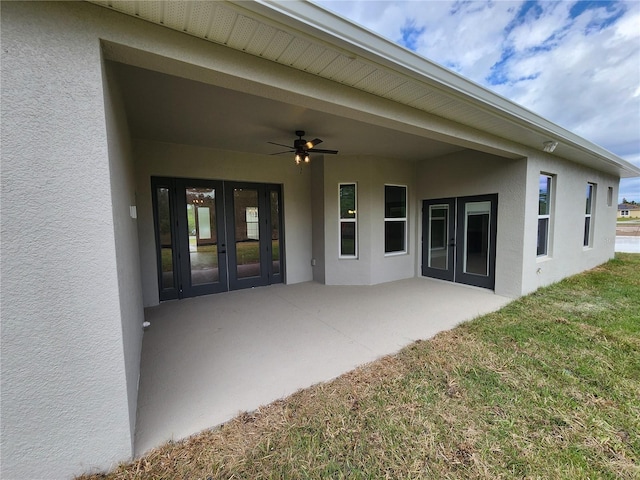 back of property with a lawn, a ceiling fan, a patio, french doors, and stucco siding