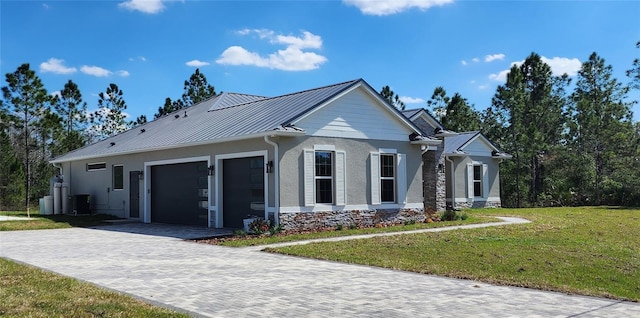 view of front facade featuring metal roof, an attached garage, a standing seam roof, decorative driveway, and a front lawn