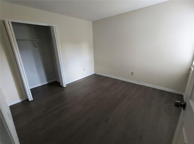 unfurnished bedroom featuring a closet and dark wood-type flooring