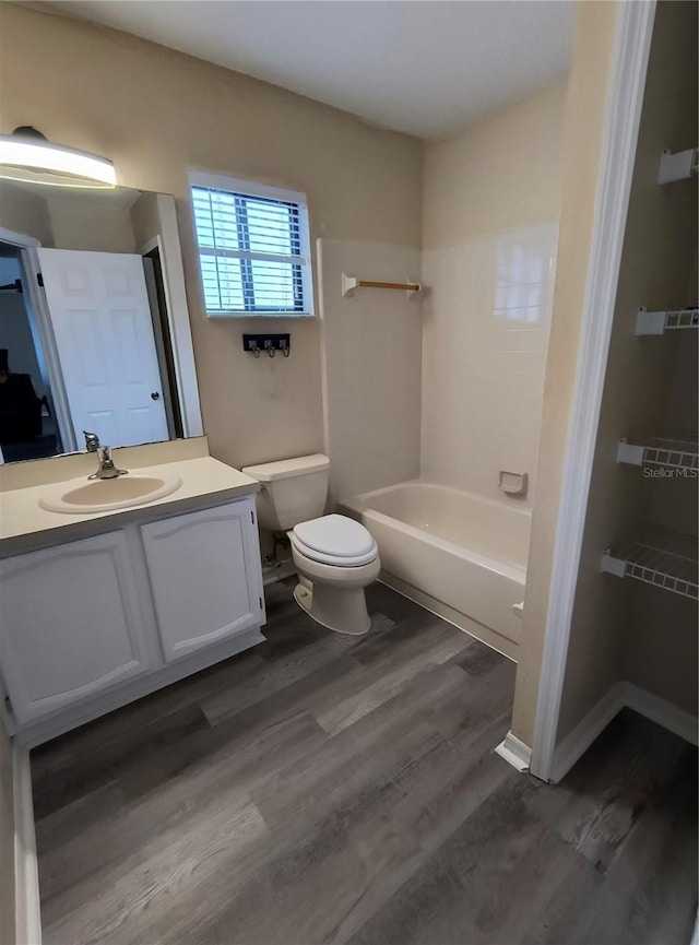 full bathroom with hardwood / wood-style flooring, vanity, toilet, and washtub / shower combination