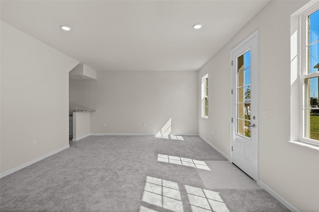 unfurnished living room featuring light carpet and plenty of natural light