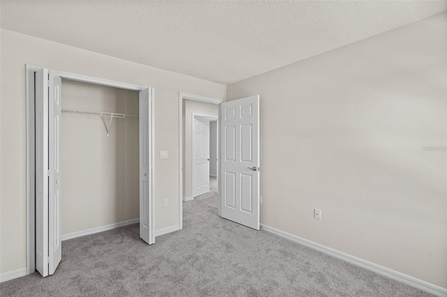 unfurnished bedroom with light carpet, a closet, and a textured ceiling