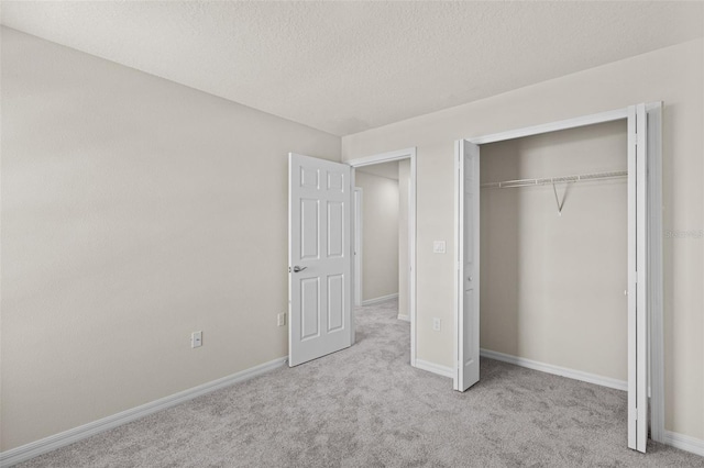 unfurnished bedroom with light colored carpet, a textured ceiling, and a closet