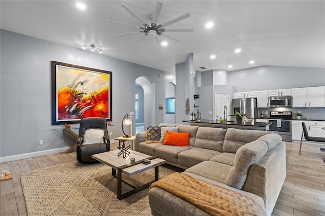 living room with light hardwood / wood-style floors, vaulted ceiling, and ceiling fan