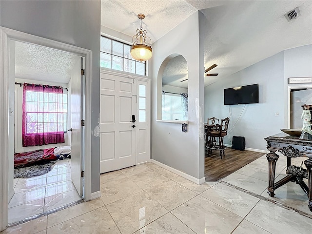 entryway featuring lofted ceiling, ceiling fan, and a textured ceiling