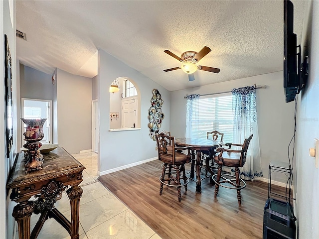 dining space with ceiling fan, light hardwood / wood-style flooring, and a textured ceiling