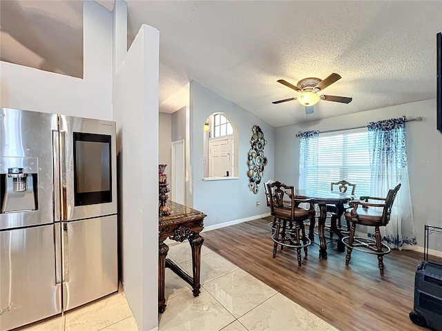 dining space with ceiling fan, a textured ceiling, and light wood-type flooring