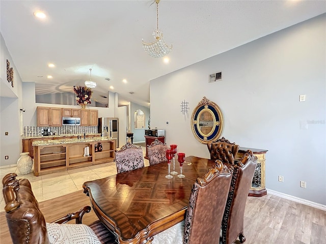 dining space featuring sink, an inviting chandelier, vaulted ceiling, and light wood-type flooring