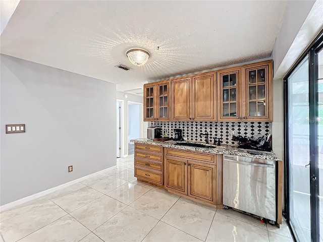 kitchen featuring tasteful backsplash, light stone countertops, stainless steel dishwasher, and a textured ceiling