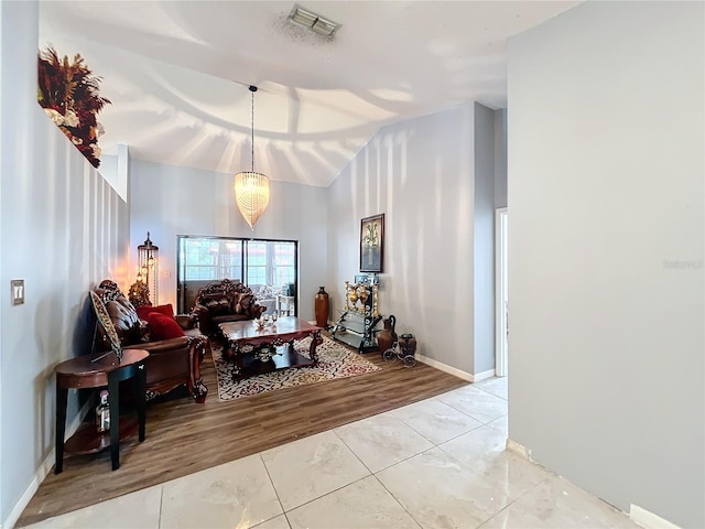 living room with a chandelier, light hardwood / wood-style flooring, and lofted ceiling