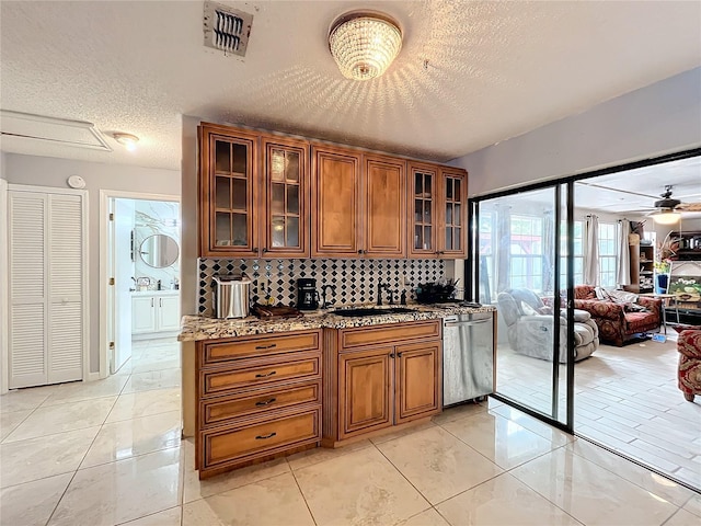 bar featuring dishwasher, sink, tasteful backsplash, light stone counters, and a textured ceiling