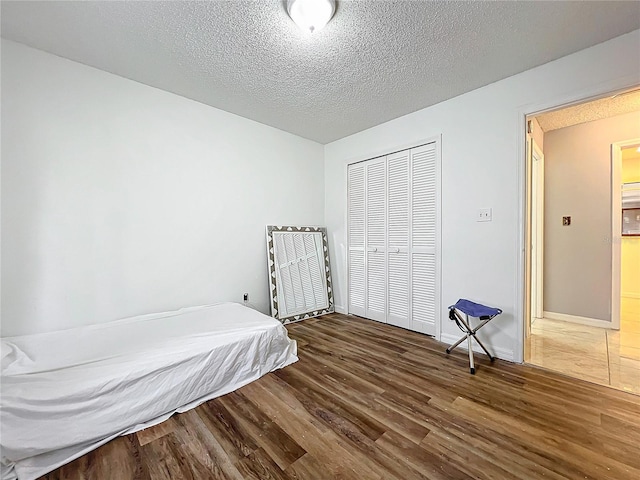 bedroom featuring a closet, dark hardwood / wood-style flooring, and a textured ceiling