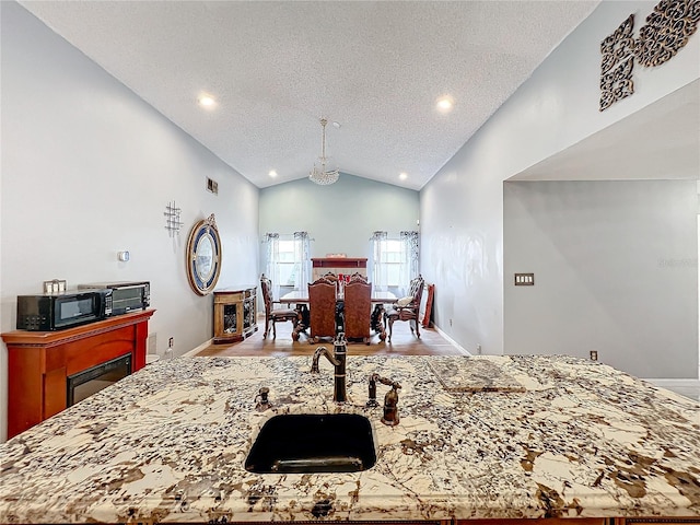 bedroom featuring a textured ceiling, high vaulted ceiling, light hardwood / wood-style flooring, and sink